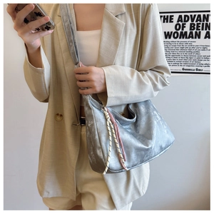 Dettaglio della borsa hobo metallizzata argento con ciondolo intrecciato su outfit casual