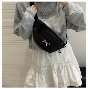 Close-up of black nylon crossbody bag featuring pink bow embroidery and adjustable strap