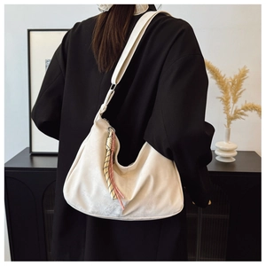 Vista dettagliata di una borsa hobo crema con nappe colorate su un blazer nero elegante