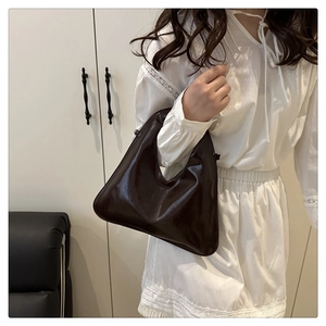 Detail of dark brown glossy leather handbag with minimalist triangular silhouette