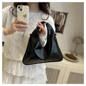 Chic black patent leather handbag with glossy finish and modern geometric crescent silhouette