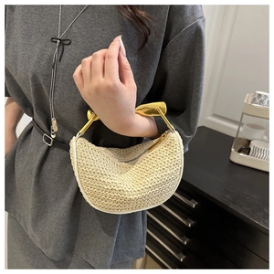 Detail of hand-woven straw handbag featuring a gold metal handle and knit texture
