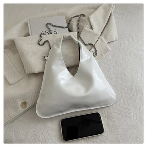 Borsa a triangolo in pelle verniciata bianca con catena d'argento su blazer di velluto