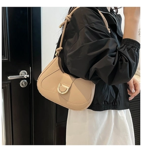 Detail of beige crescent underarm bag with gold D-buckle and textured faux leather finish