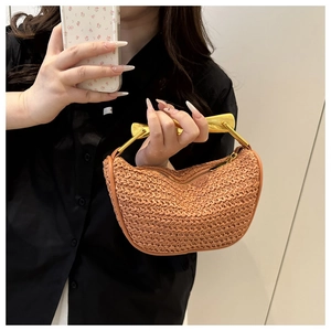 Detail of hand-woven saddle bag with textured raffia and gold-tone metal handle