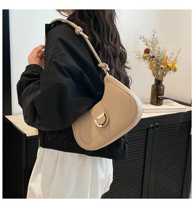 Detail of beige crescent shoulder bag with golden D-ring buckle and decorative knot