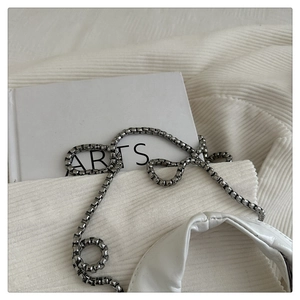 Detailaufnahme der weißen Stofftasche mit gerippter Textur und silberner Gliederkette