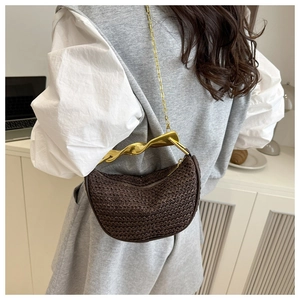 Detailed close-up of dark brown woven straw bag with a unique gold twisted handle