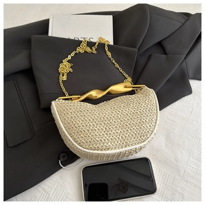 Detail of a beige woven half-moon bag with gold metal handle and chain strap on a blazer