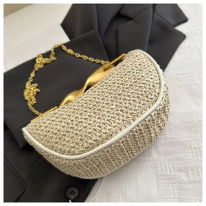 Detail of straw woven handbag featuring gold wavy handle and white trim finish