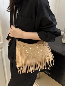 Beige faux suede crossbody bag featuring gold studs and bohemian tassel fringe