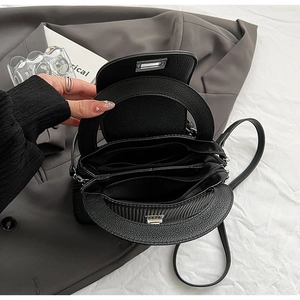 Interior detail of black quilted bag showing multi-layer compartments and silver hardware