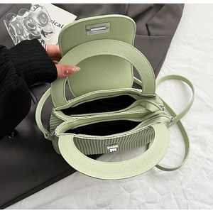 Detail of light green litchi grain leather bag with dual zipper compartments and handle