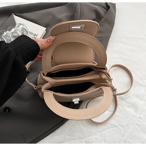 Detail of beige quilted handbag with dual zipper compartments and leather texture