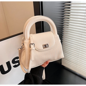 Close-up of cream crossbody bag featuring vertical rib texture and silver twist lock