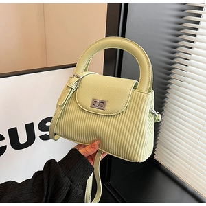 Detail of pistachio green mini bag featuring textured vertical stripes and silver twist lock