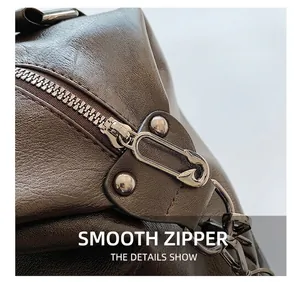 Close-up of vintage brown leather tote bag showing a unique pin-shaped metal zipper detail