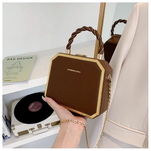 Detail of a brown vintage box bag with woven handle, gold frame and metal chain strap