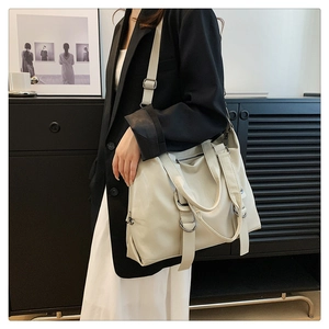 Detail of large creamy white tote bag with silver metal rings and soft PU leather texture