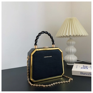 Detail of black octagonal box bag with gold metal frame and woven spiral handle