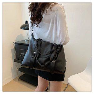 Detail of a large black tote bag showing smooth matte texture and adjustable shoulder strap