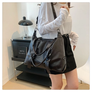 Detailed view of spacious black PU leather tote bag with wide shoulder strap and silver hardware