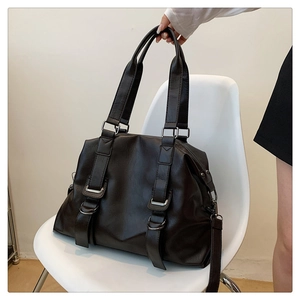Detail of vintage dark brown faux leather tote bag with silver buckles on a white chair