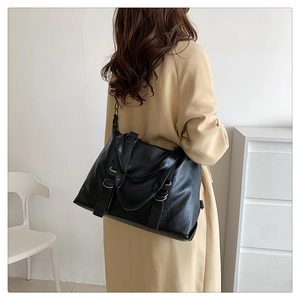 Detail view of large black matte leather tote bag with adjustable strap and metal rings