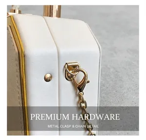 Detail showing white leather texture with gold metal trim and chain lobster clasp hook