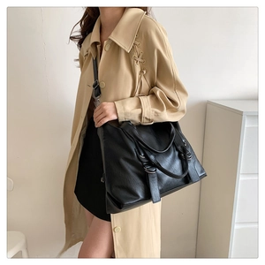 Detailed view of black leather tote bag worn by model featuring large capacity and straps