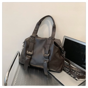 Detail of dark brown retro tote bag with dual handles and metal buckle decorations