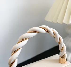 Detailed close-up of woven cream leather handle with gold metallic accents on handbag