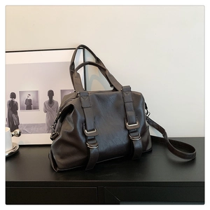 Detail of vintage dark brown tote bag with leather straps and metallic hardware accents