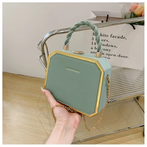 Close-up of light green octagon box bag featuring gold hardware and spiral handle