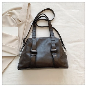 Detail of vintage tote bag in dark brown faux leather with decorative straps and metal buckles