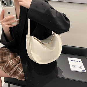 Minimalist off-white half-moon tote bag with shoulder strap worn by a female model