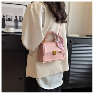 Pink flap crossbody bag with golden twist lock and decorative floral scarf on handle