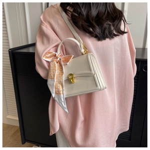 Detailed side view of cream square handbag with accordion folds and printed silk scarf