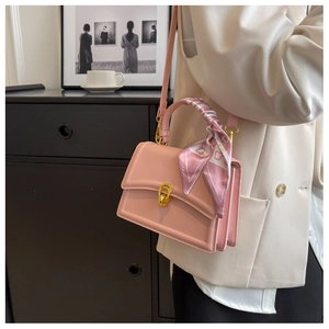 Pink square leather handbag with scarf handle and gold twist lock shown on model