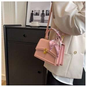 Pink PU leather crossbody bag featuring a golden twist lock and silk scarf handle detail