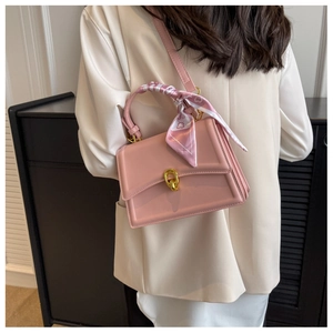 Detail of pink crossbody bag with gold twist lock and elegant silk scarf handle