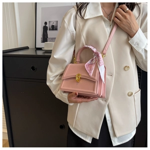 Pink square handbag with floral silk scarf handle held by model in home setting