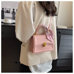 Pink square handbag with silk scarf handle detail and gold twist lock shown on model