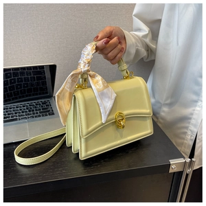 Detail of cream yellow square bag with gold twist lock and printed scarf on handle
