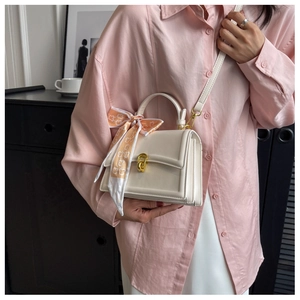 Detail view of white leather crossbody bag with floral silk scarf and gold twist lock