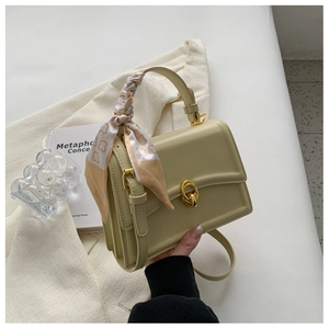 Detail of cream yellow leather square bag with decorative silk scarf and gold ring clasp
