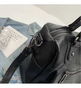 Close-up of shiny black leather bag with premium silver metal hardware and side zipper detail