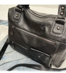 Detail of black multi-zipper leather bag with metal rivets and adjustable strap