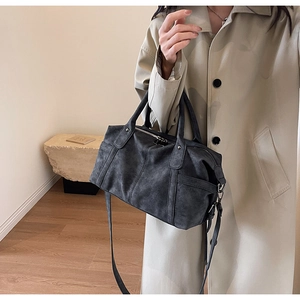 Detailansicht der Vintage-Boston-Tasche in Rauchgrau, gestylt mit einem klassischen beigen Trenchcoat