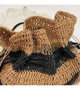 Detailed close-up of straw woven tote featuring black leather drawstring and ruffles